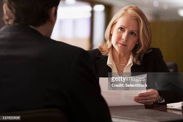 mature businesswoman interviewing male candidate - serious interview stock pictures, royalty-free photos & images