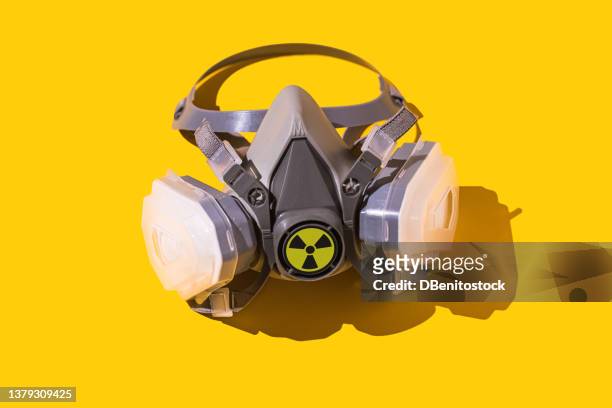 protective mask with nuclear symbol on yellow background. concept of nuclear, energy, supply, disaster, fight, confrontation, chemical weapon, danger and chernobyl. - radioactive warning symbol photos et images de collection
