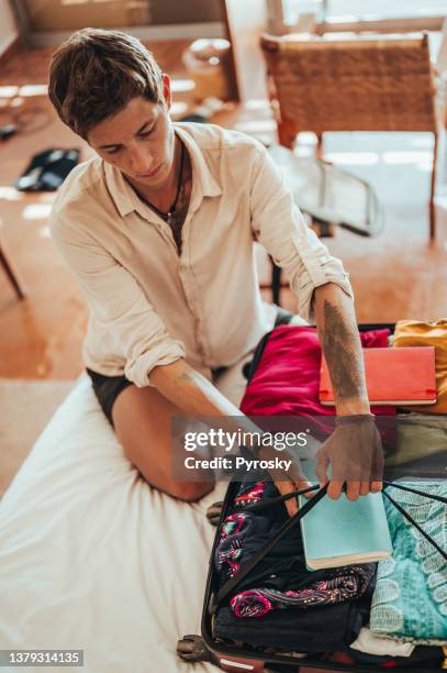 an urban young man is packing for the trip - closing book stock pictures, royalty-free photos & images