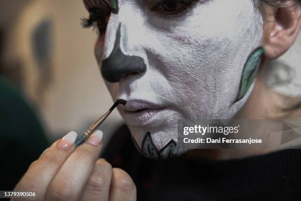 close-up of a theater actress applying face paint in her dressing room before going on stage in a halloween-related play. - female body painting 個照片及圖片檔