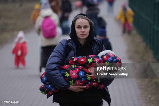 Women and children from war-torn Ukraine, including a mother carrying an infant, arrive in Poland at the Medyka border crossing on March 04, 2022...