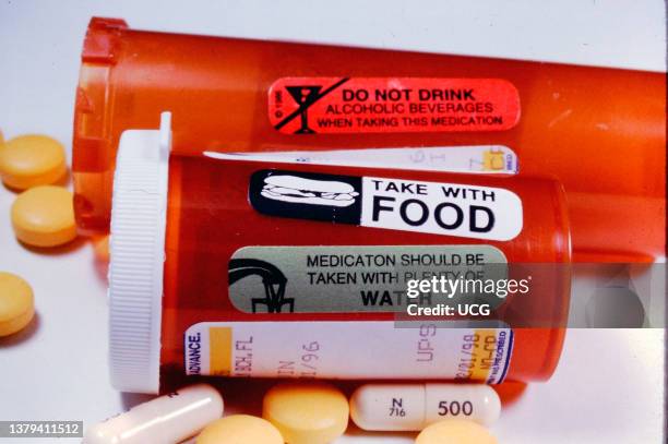 Group of prescription drugs with warning labels about taking with food, water and not alcohol.