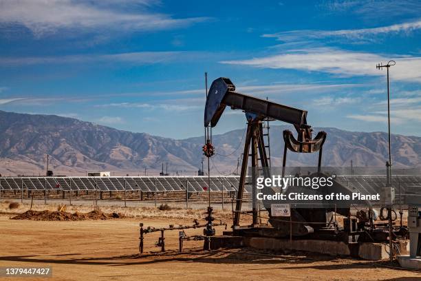 Lone pumpjack located in the middle of large solar array outside of Bakersfield, Kern County, California, USA.