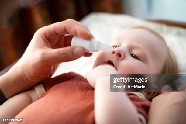 父は彼の赤ちゃんの女の子の鼻の滴を与える - 生理食塩水 ストックフォトと画像