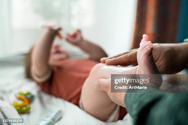 father applying moisturizing and protective cream to his baby girl - moisturiser stock pictures, royalty-free photos & images