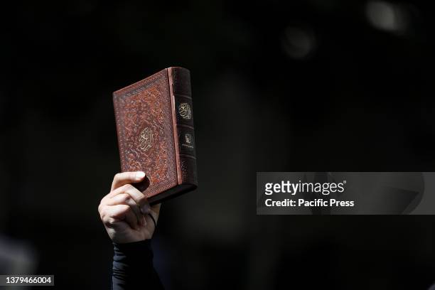 An Iranian demonstrator holds up a copy of Quran, Islam's holy book in front of the Swedish Embassy during a protest of the burning of a Quran in...