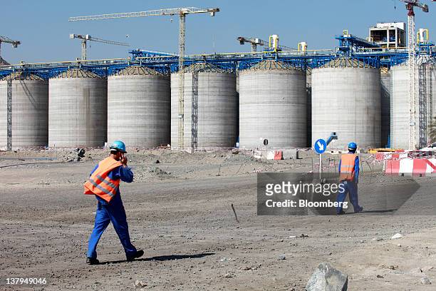 Workers pass storage containers under construction at Fujairah port in Fujairah, United Arab Emirates, on Friday, Jan. 27, 2012. The Abu Dhabi Crude...