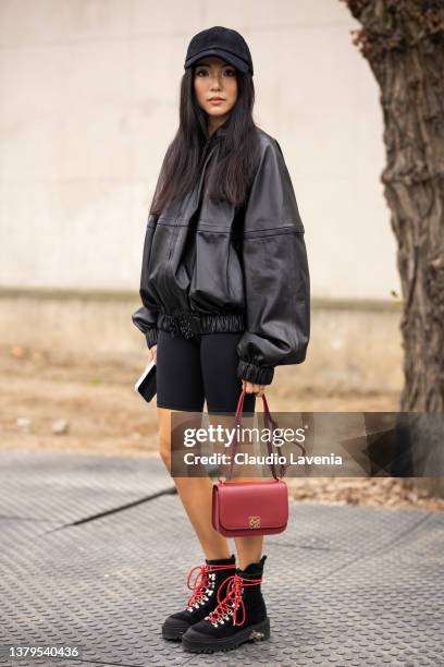 Yoyo Cao wearing a black leather jacket, black biker shorts, black hat, black boots and red Loewe bag, is seen outside Loewe, during Paris Fashion...