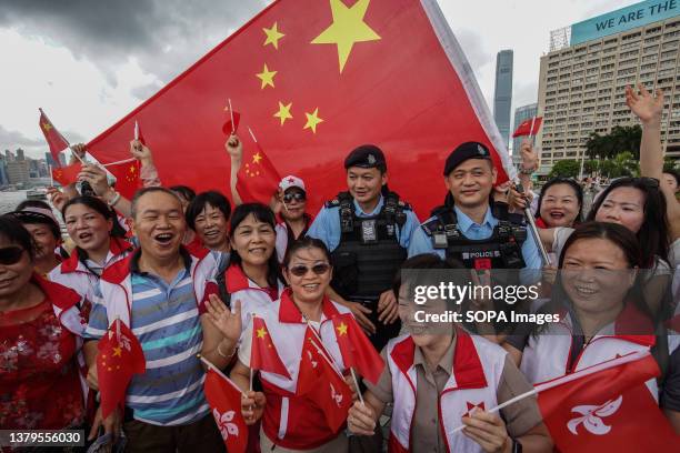 People wave both the flags of China and Hong Kong with two police officers at Tsim Sha Tsui. On July 1st Hong Kong commemorates the 26th anniversary...