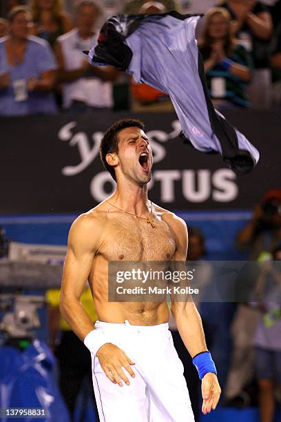 Novak Djokovic of Serbia rips his shirt off after winning championship point in his men's final match against Rafael Nadal of Spain during day...