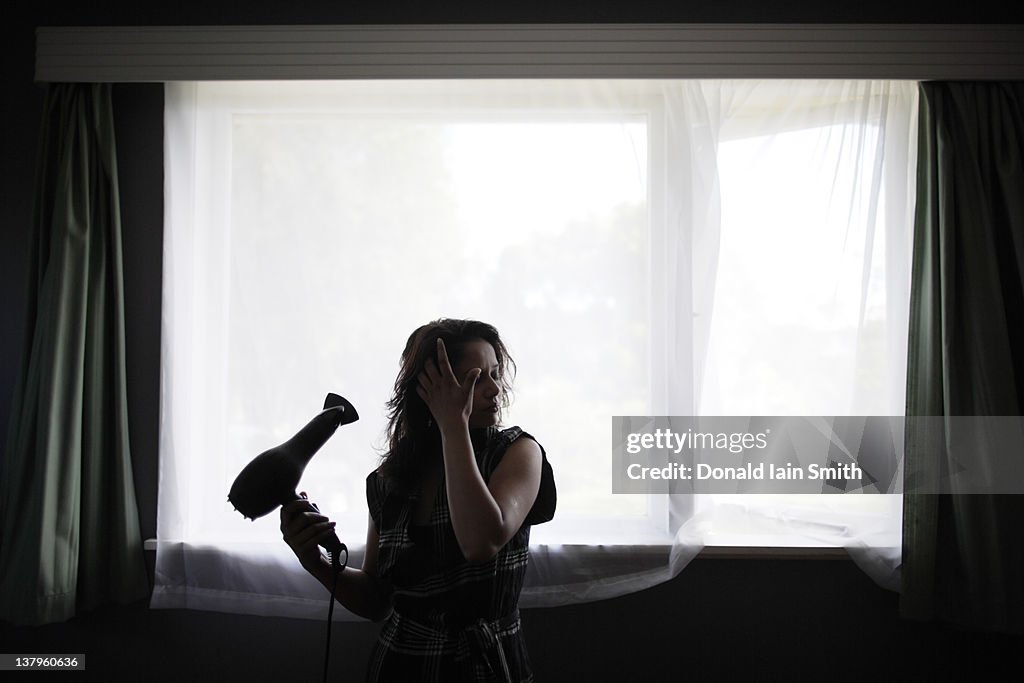 Woman at window with hairdryer