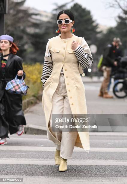 Guest is seen wearing a cream coat vest, Loewe striped sweater, cream pants and Loewe sunglasses outside the Loewe show during Paris Fashion Week A/W...