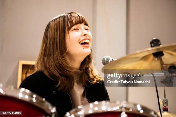 the drummer of a female band happily talking while practicing in a music studio. - ドラム ストックフォトと画像