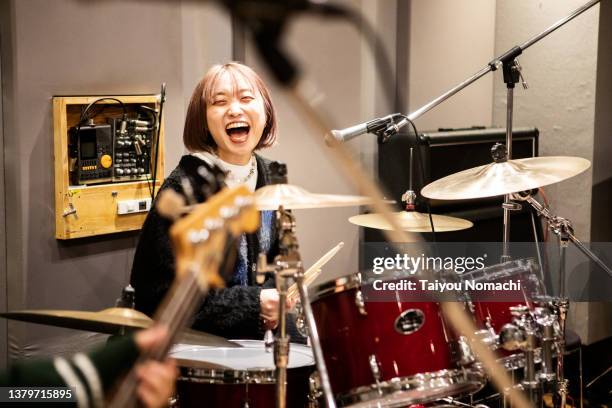 a female drummer laughs while practicing in a music studio. - playing drums fotografías e imágenes de stock