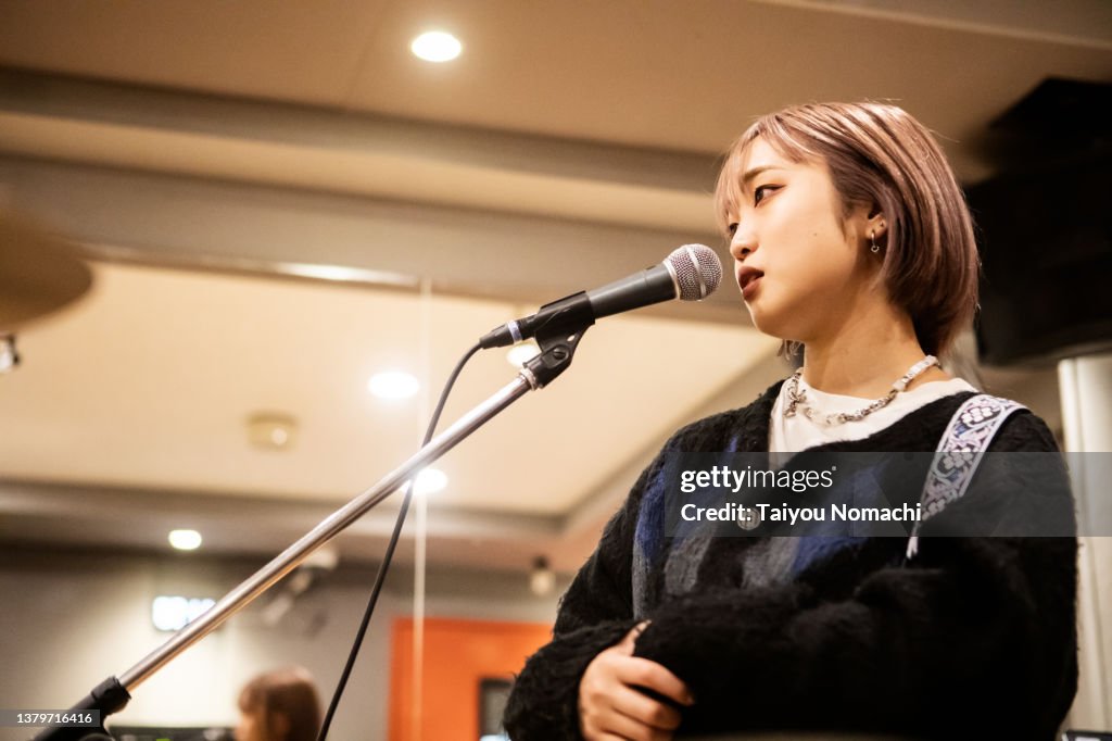 A female singer looks serious while practicing in a music studio.