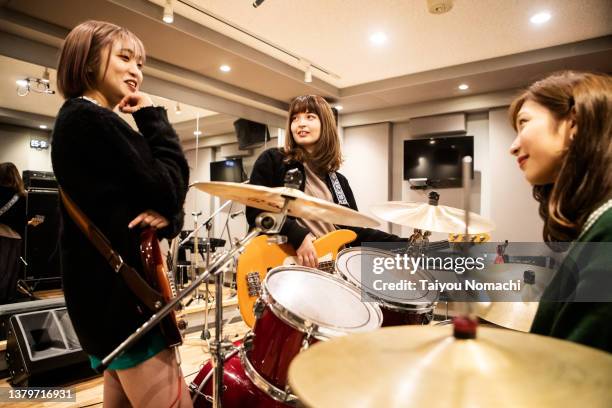 members of a female band begin to discuss during a practice session at a music studio. - woman electric guitar stock pictures, royalty-free photos & images