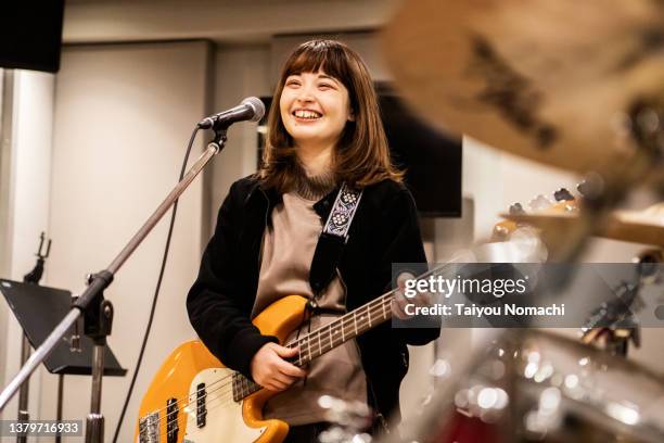 a bassist in a female band practicing with her friends in a music studio. - woman playing guitar stock pictures, royalty-free photos & images