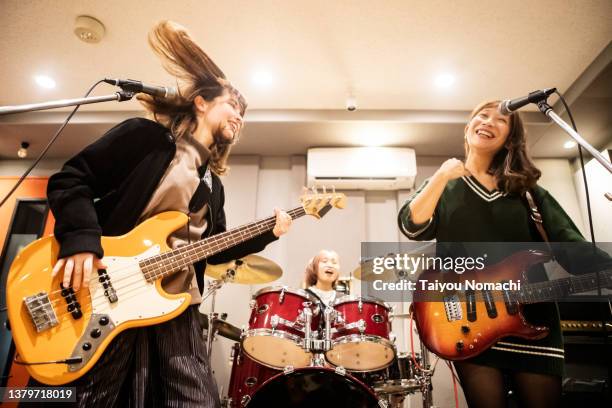 members of a female band practicing happily in a music studio. - woman electric guitar stock pictures, royalty-free photos & images