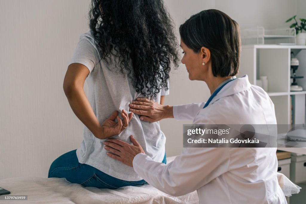 Faceless african-american patient complaining about back ache and rheumatism to orthopedist