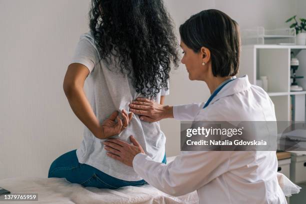 faceless african-american patient complaining about back ache and rheumatism to orthopedist - osteopathie stockfoto's en -beelden