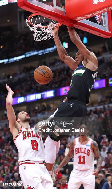 Giannis Antetokounmpo of the Milwaukee Bucks dunks over Zach LaVine of the Chicago Bulls at the United Center on March 04, 2022 in Chicago, Illinois....