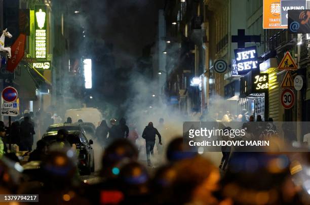 Demonstrators run as French police officers use tear gas in Paris on July 2 five days after a 17-year-old man was killed by police in Nanterre, a...