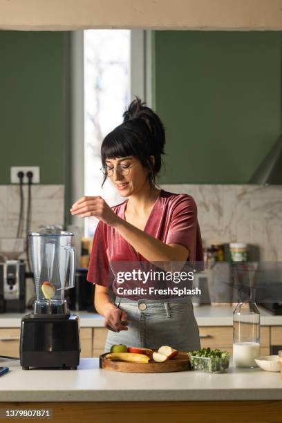 joven feliz preparando un desayuno saludable en casa - licuadora fotografías e imágenes de stock