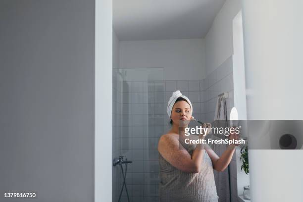 beautiful overweight caucasian woman applying makeup in the bathroom - women taking showers stock pictures, royalty-free photos & images