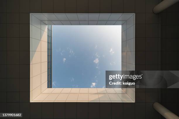 looking up at the blue sky through the large skylight on the roof of the building - oberlicht stock-fotos und bilder