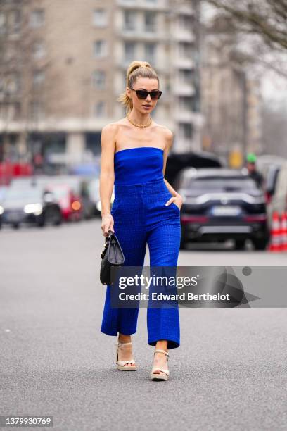 Guest wears black sunglasses, gold earrings, a gold chain necklace, a royal blue electric shoulder-off top, matching royal blue electric tweed wide...