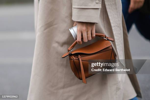 Guest wears a beige long coat, a brown camel shiny Small Puzzle bag in classic calfskin handbag from Loewe, outside Loewe, during Paris Fashion Week...