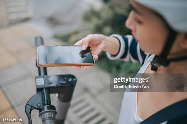 asian chinese female using mobile app unlocking electric push scooter for city travel commuting - protective sportswear stock pictures, royalty-free photos & images