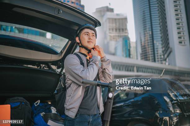 asian chinese man getting ready for push scooter riding in city during morning in front of car trunk - step well stockfoto's en -beelden