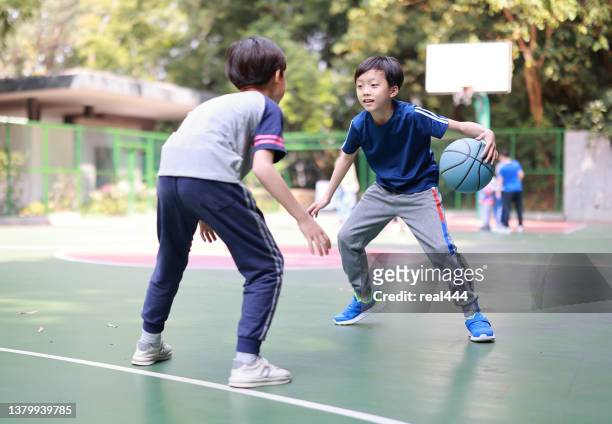 two boys playing basketball outside - blocking sports activity stock pictures, royalty-free photos & images