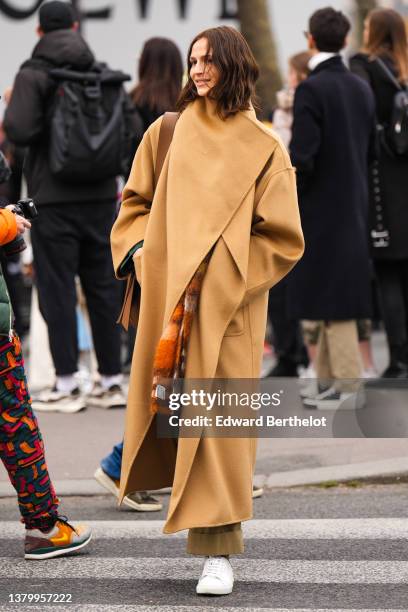 Guest wears a brown beige oversized long coat, a brown shiny leather shoulder bag, a brown / beige / orange checkered print pattern wool scarf from...