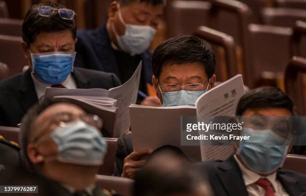Chinese attendees follow along during speeches at the opening session of the National Peoples Congress at the Great Hall of the People on March 5,...