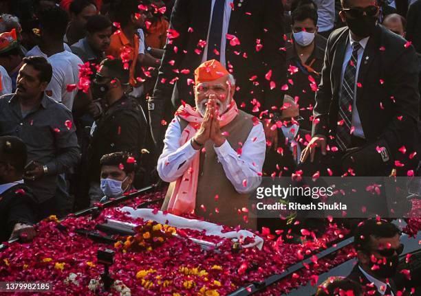 India's Prime Minister Narendra Modi greets crowds of supporters during a roadshow in support of state elections on March 04, 2022 in Varanasi,...