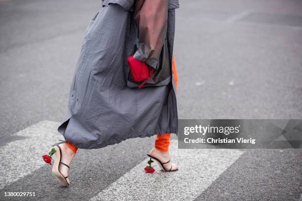 Gala Gonzalez seen wearing grey see trough Loewe rain coat, orange hoody, pants with logo print, red micro bag, heeled sandals outside Loewe during...