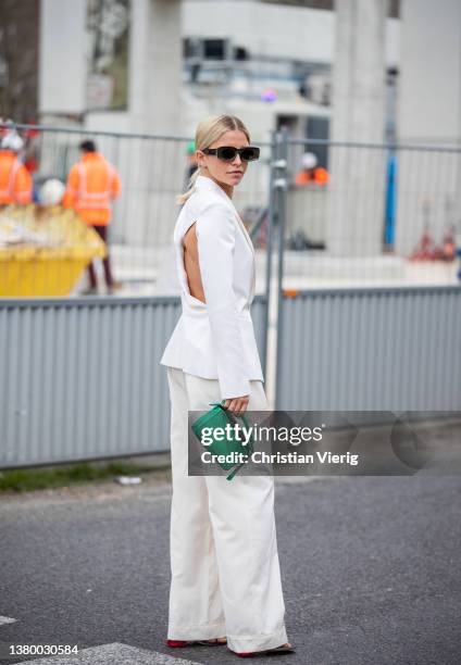 Caroline Caro Daur seen wearing white blazer, pants, green Loewe bag, black sunglasses, necklace, heeled sandals outside Loewe during Paris Fashion...