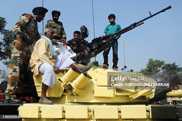 The parent of an Indian army serviceman sits on top of a T-72 tank during an Indian Army weaponry exhibition in Kolkata on January 31, 2012. The...