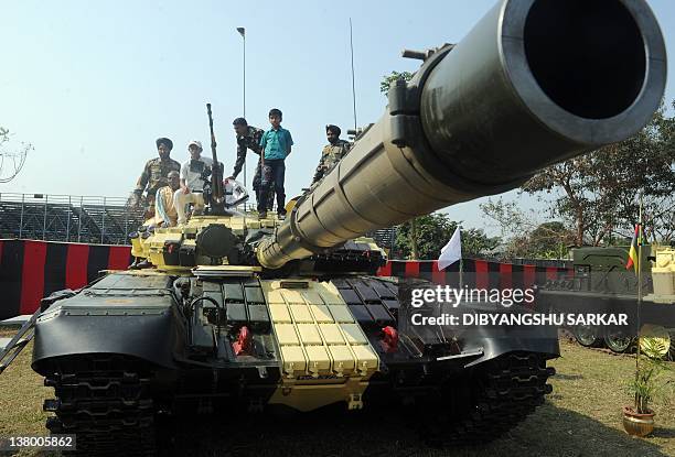 Civilian visitors sit on top of a T-72 tank during an Indian Army weaponry exhibition in Kolkata on January 31, 2012. The event showcased the...