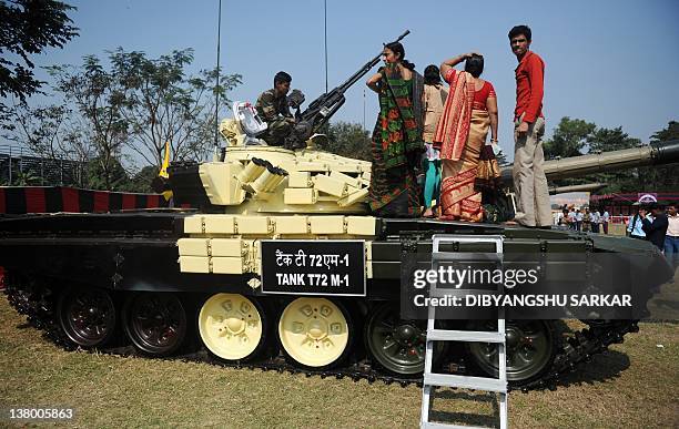 Civilian visitors sit on top of a T-72 tank during an Indian Army weaponry exhibition in Kolkata on January 31, 2012. The event showcased the...