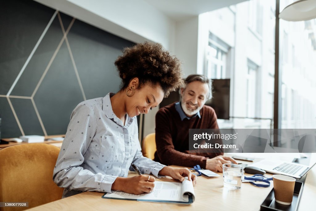 Newly employed African American woman signing contract in new company