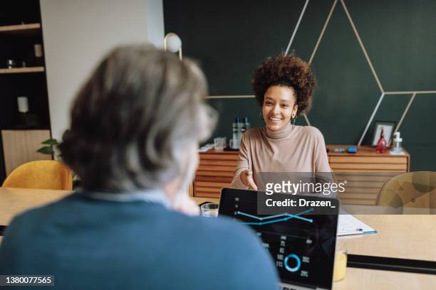 donna d'affari multirazziale sorridente con capelli afro che parla con un consulente finanziario - finanza ed economia foto e immagini stock