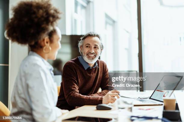 conseiller financier et homme d’affaires souriant parlant à une collègue métisse au bureau - boss photos et images de collection