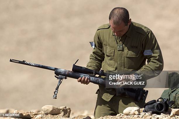 An Israeli army sniper cleans his gun after an exercise at the Shizafon army base, in the Negev Desert north of the southern city of Eilat, on...