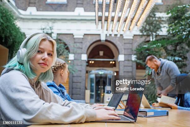 beautiful teenage female student studying in a public library - linguistics stock pictures, royalty-free photos & images