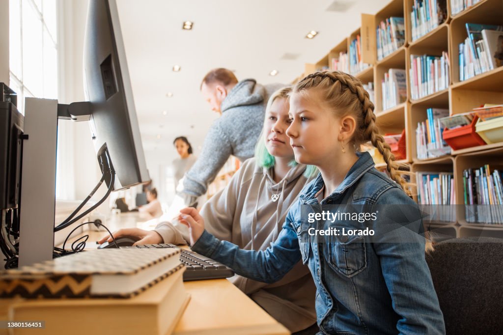 Two beautiful female sister students studying in a public library