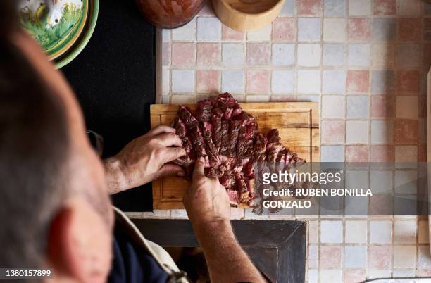 high view of tomakawk steak on cutting board in a kitchen and man preparing tomakawk steak on a kitchen counter. food and drink concept. - gonzalo caballero fotografías e imágenes de stock