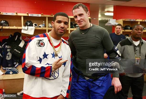 Musical rap artist Drake visits Dion Phaneuf of the Toronto Maple Leafs and team Chara in the locker room during the first intermission of the 2012...